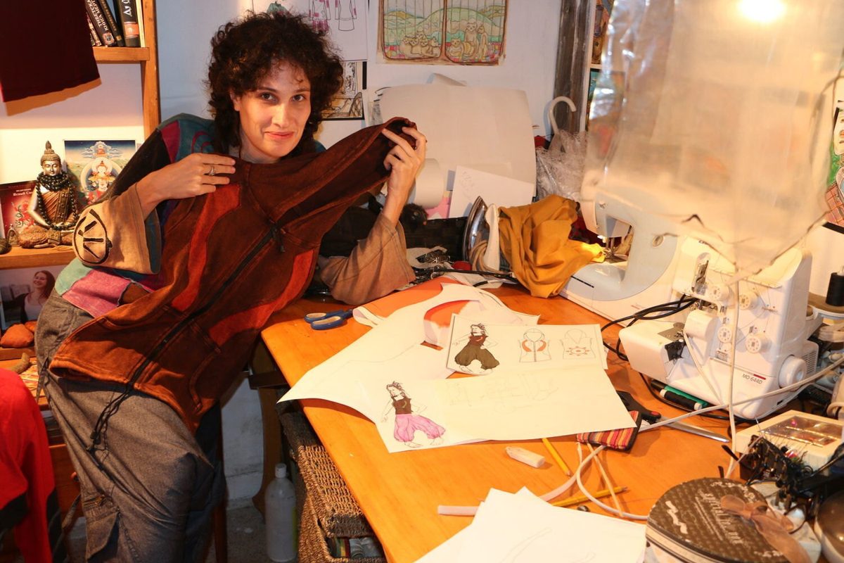 Jenia, founder of manaKAmana, at her sewing table with a new design