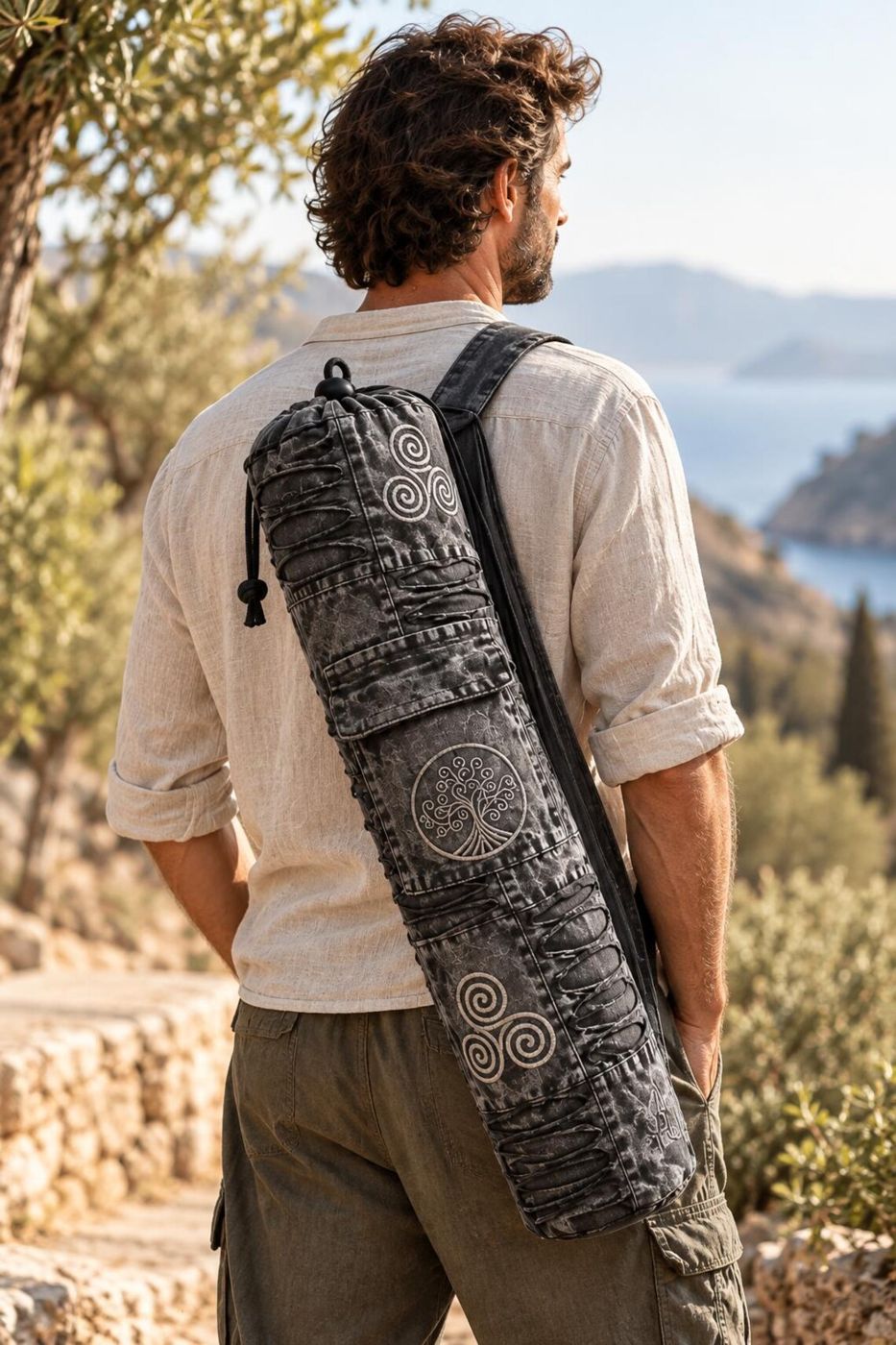 Man carrying the yoga mat bag across his back by the sea